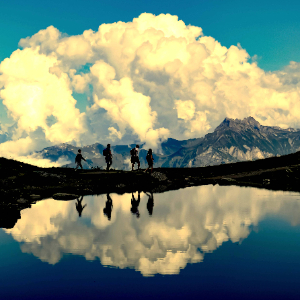 Escursionisti in trekking con laghetto alpino e cielo nuvoloso